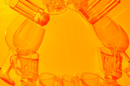 Set of empty drink glasses with shadows and sun highlights in the sunset light. Glassware arranged on an orange background with shadows. Top viewの写真素材