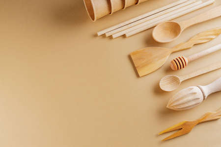 Set of eco friendly wooden bamboo cutlery on beige background. Plastic free concept. Disposable paper cups and wooden kitchenware on earth color background. Zero waste conceptの写真素材