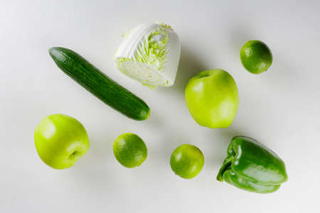 Green vegetables and fruits on white background. Healthy vegetarian food concept. Top view