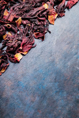 Flowers red hibiscus tea. Dry hibiscus petals on a dark background. Karkade, red tea, aromatic hibiscus tea. top view. copy spaceの写真素材