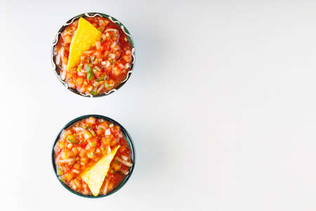Two bowls with salsa sauce and nacho chips on a white background. Tortilla chips and salsa dip in bowl. Mexican food concept. top view. copy spaceの写真素材