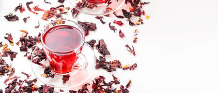Cup of hibiscus tea (rosella, karkade, red sorrel) on a white background. Hibiscus tea and dry hibiscus petals. Diuretic drink with herbs. top view. copy spaceの写真素材
