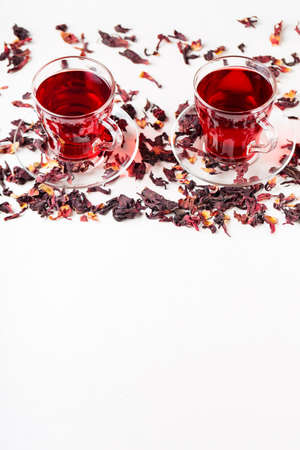 Cup of hibiscus tea (rosella, karkade, red sorrel) on a white background. Hibiscus tea and dry hibiscus petals. Diuretic drink with herbs. top view. copy spaceの写真素材