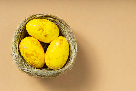 Yellow easter eggs in nest on beige background. Minimal Easter concept. top view. copy space