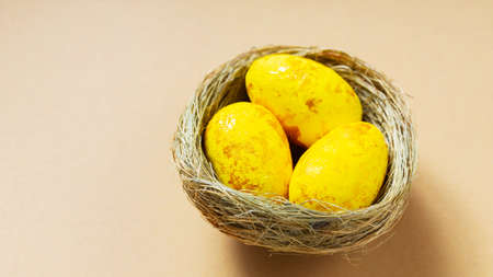 Yellow easter eggs in nest on beige background. Minimal Easter concept. top view. copy space
