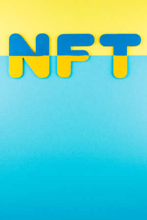 NFT inscription on a blue-yellow background. Non-fungible token in colors of Ukrainian flag....
