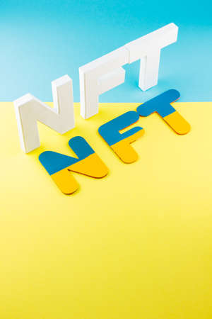 NFT inscription with white 3d letters on a blue-yellow background. Non-fungible token against...