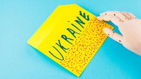 Yellow envelope with red spots on a blue background. Artificial arm holds an envelope with the...