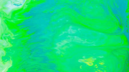 Fluid art background in green color. Green-turquoise stains on liquid. Creative background with blurred paints. Background for an eco-friendly conceptの写真素材