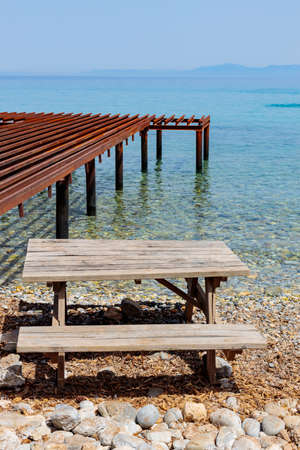 Wooden table and bench on the seashore. Handmade picnic table near the sea. Place for rest travel...