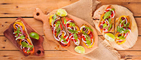 Spanish tapas and lime on a cutting board. Bruschetta with tomatoes, greens and olives. Healthy open...
