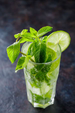 Mojito cocktail on a dark background. Summer cocktail with lime, mint and ice cubes. Refreshing citrus drinkの写真素材