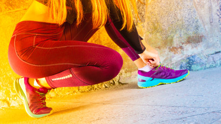 Young sportswoman stretching before running. Girl in sportswear is warming up on the background of a...