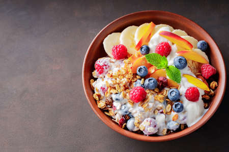Granola breakfast with yogurt, blueberry, raspberry, banana and peach. Healthy breakfast with...