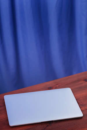 Closed laptop on a wooden table. Silvery laptop at workplace in home office. Work from home concept