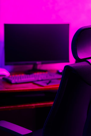 Creative designer's workplace, back view. Office chair and work desk view with graphic tablet, computer and smartphone. Retoucher home office in neon pink blueの写真素材
