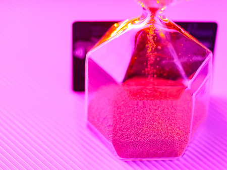 Bank card and hourglass on a purple background. Sandglass and credit card in neon light. Time is...