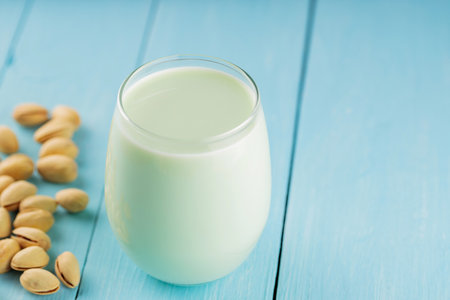 Pistachio milk in glass on blue boards. Vegan nutty plant based milk. Diet milk, vegetarian foodの写真素材