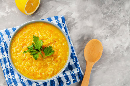Red Lentil Soup with ingredients on a gray background. Bowl of lentil soup and a wooden spoon on a linen napkin. top viewの写真素材