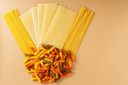 pasta. Different types of raw pasta on a beige background. Creative composition with lasagna, spaghetti and fusilli. Italian food conceptの写真素材