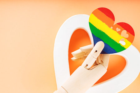 Heart in rainbow colors in artificial arm on coral background. LGBT equal rights movement and gender equality concept. copy spaceの写真素材