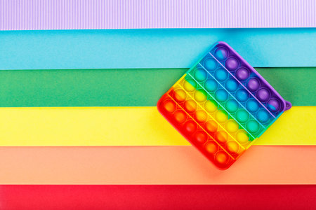 Colorful trendy  fidgets toy on rainbow background. LGBT equal rights movement and gender equality concept. copy spaceの写真素材