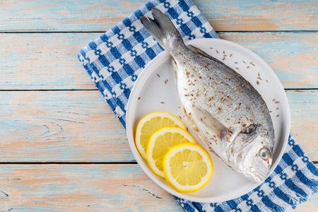 Fresh raw dorado fish with spices and lemon on old boards. Copy spaceの写真素材