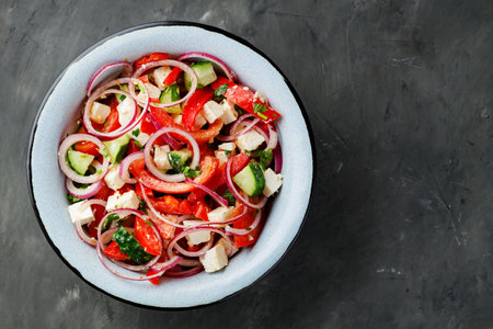 Fresh vegetable salad with feta cheese on dark concrete background. Top view. Copy spaceの写真素材