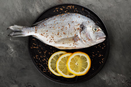 Dorado Fish with Lemon and Cumin Seeds on Black Plate, Close upの写真素材