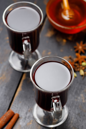 Warm mulled wine with cinnamon, anise and citrus fruits on wooden table. Autumn and winter drinksの写真素材