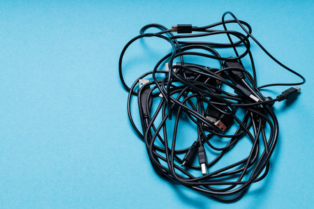Tangled Black Cables for Modern Gadgets on Blue Background, Copy Spaceの写真素材