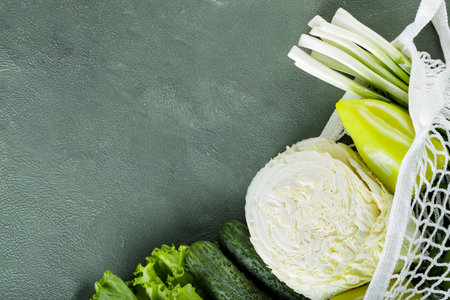 Fresh Green Vegetables in Mesh Bag on Green Background, Copy Space