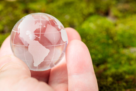 Transparent Glass Globe Held in Man's Palm, Concept of Earth Day and Environmental Protectionの写真素材