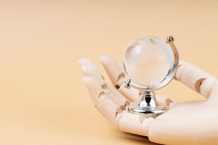 Glass Globe in Cyborg's Palm on Beige Background, Concept of Technological Protection from Environmental Disastersの写真素材