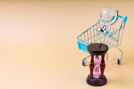 Shopping Cart with Globe and Hourglass on Beige Background, Time for Change Concept