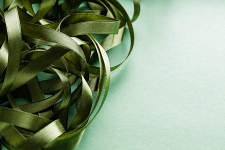 Tangled Green Christmas Ribbon on Monochrome Green Background for Festive Holiday Decor, Copy Spaceの写真素材