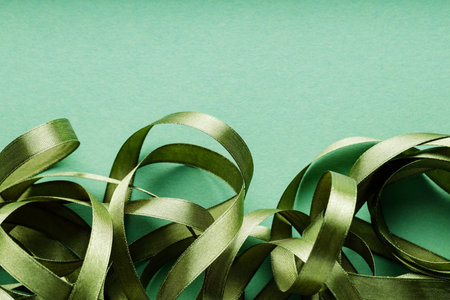 Tangled Green Christmas Ribbon on Monochrome Green Background for Festive Holiday Decor, Copy Spaceの写真素材