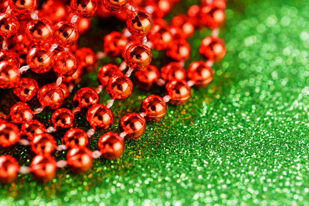 Vibrant Red Beads on Glittery Green Background for Traditional Christmas and New Year Decoration, Copy Spaceの写真素材