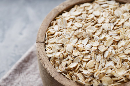 Oat Flakes in Wooden Bowl on Linen Napkin, Healthy Whole Grain Breakfast, Close-Upの写真素材
