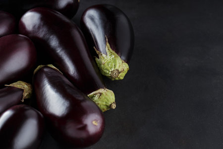 Pile of Freshly Harvested Eggplants on Dark Background, Organic Ecological Food, Copy Space, Top Viewの写真素材