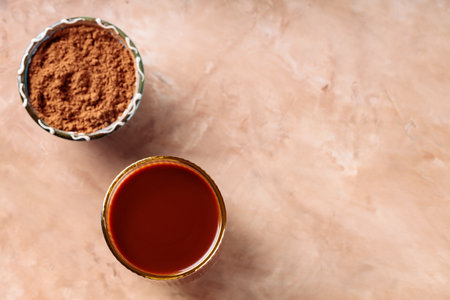 Cocoa Drink in Gold-Rimmed Glass and Bowl with Cocoa Powder on Textured Peach Surface, Copy Spaceの写真素材