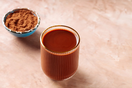 Cocoa Drink in Glass and Cocoa Powder in Bowl on Brown Background, Copy Spaceの写真素材