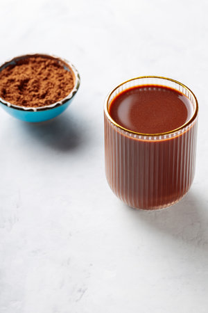 Cocoa Drink in Ridged Glass with Gold Rim and Bowl of Cocoa Powder on Concrete Background, Copy Spaceの写真素材