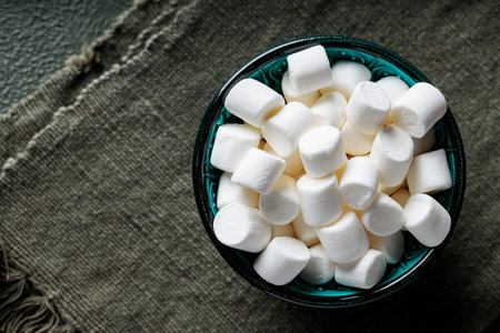 White Marshmallows in Turquoise Bowl on Green Napkin Top View Copy Space