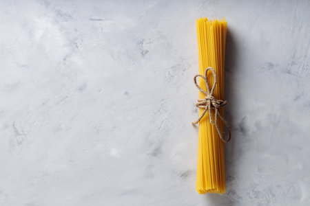 Uncooked Spaghetti Pasta with Natural Rope on Gray Background Top View Copy Spaceの写真素材