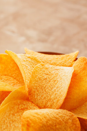 Crispy Golden Potato Chips in Bowl on Beige Background Close-Up