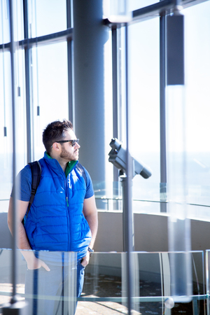 Close up of a young handsome man with black beard and modern trendy hairstyle wearing blue...