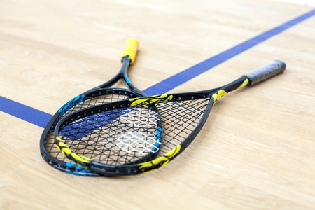 Yellow and blue tennis rackets are lying on wooden court background - sport, fitness, healthy lifestyle and objects conceptの写真素材
