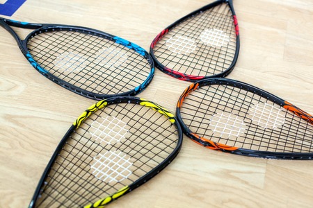 Four tennis rackets are lying on wooden court background - sport, fitness, healthy lifestyle and objects conceptの写真素材