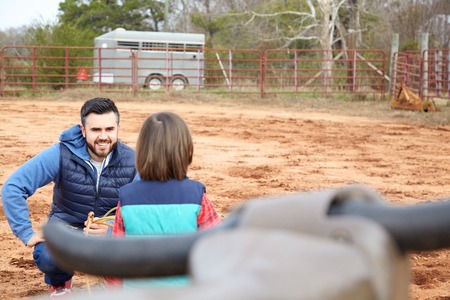 Father training small toddler boy son making loope and throwing lasso to bull in the ranch. Roping...
